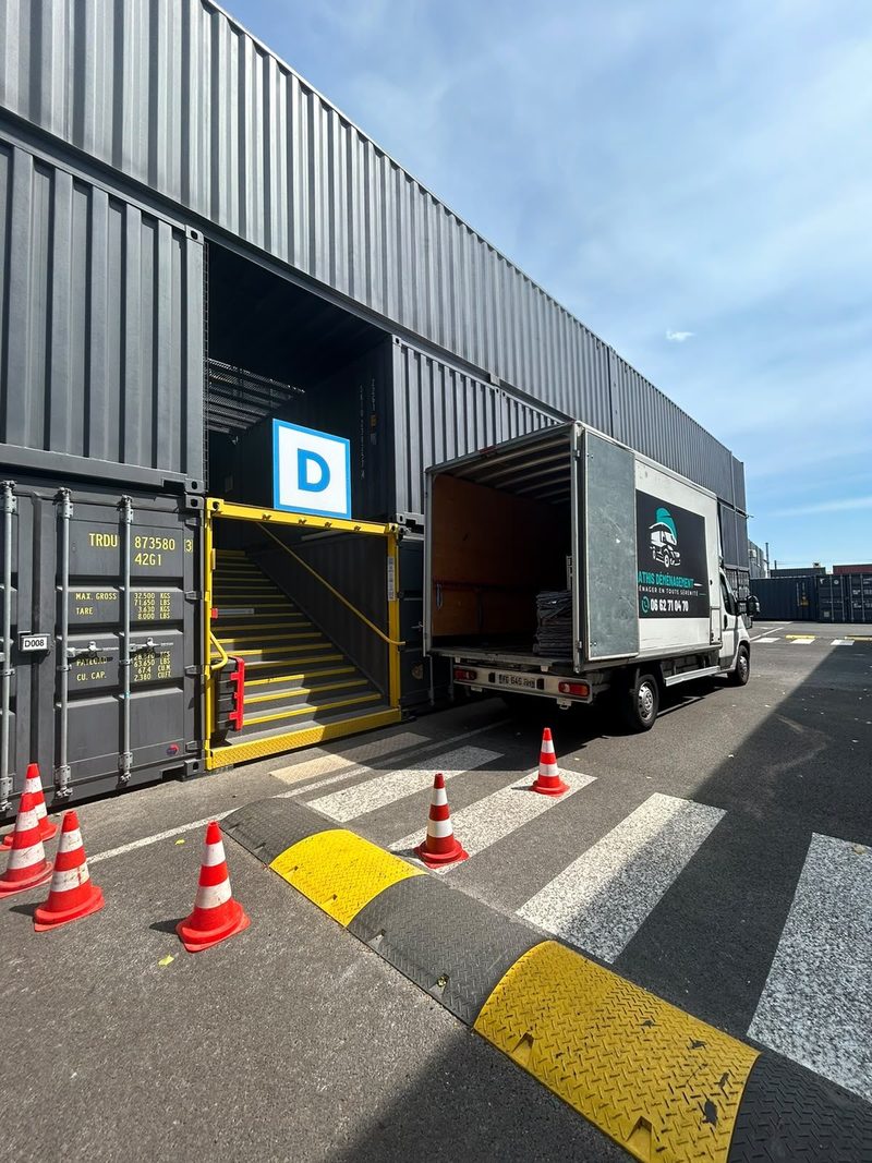 Camion à hayon élévateur devant un box de stockage, zone sécurisée par cônes