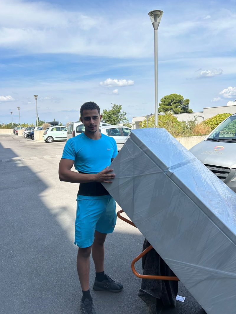 Mathis porte un meuble emballé jusqu'au camion